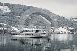 Tourist cruise in Austria Zell am See on frozen lake with snow and beautiful mountains on the background. Tourist ship boat s