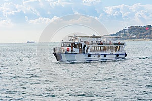 Tourist cruise sailing on the Bosphorus strait on a sunny day with background cloudy sky, Istanbul, Turkey