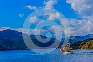 Tourist cruise ship on lake Ashi with mountains and blue sky on