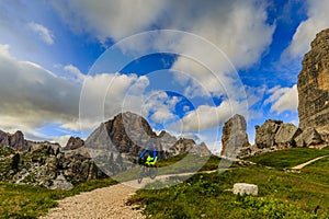 Tourist cycling in Cortina d`Ampezzo, stunning Cinque Torri and