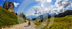 Tourist cycling in Cortina d `Ampezzo, stunning rocky mountains on the background. Woman riding MTB enduro flow trail. South Tyrol