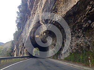 Tourist driver driving through tunnel on road carved out of rock of mountain