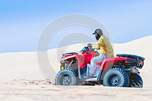 Tourist enjoy riding the quad bike or powerful fast off-road four-wheel drive ATVs at white sand dunes