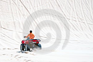 Tourist enjoy riding the quad bike or powerful fast off-road four-wheel drive ATVs at white sand dunes