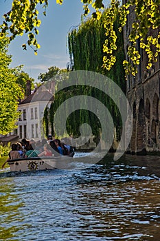 Tourist  enjoying  a boat trip along the canales on a sunny summers  day in Bruges Belgum