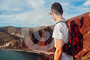 Tourist enjoying Red beach, Aegean sea landscape view in Akrotiri, Santorini island, Greece. Man backpacker travel