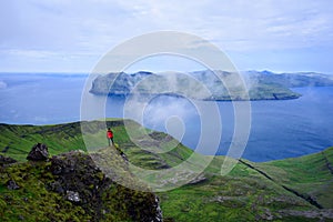 Tourist enjoying the view of Vagar Island from Mount Sornfelli in Faroe Islands