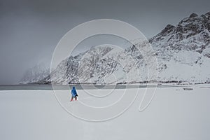 A tourist enjoys the beautiful scenery and walks on the shore on the Lofoten Islands in Norway