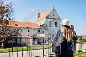 Tourist enjoys view of Capuchin monastery in Olesko, Lviv region, western Ukraine by Olesko Castle. Traveling in spring