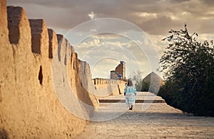 Tourist in ethnic dress at city walls Ichan Kala of Khiva