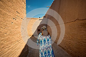 Tourist in ethnic dress at city walls Ichan Kala of Khiva