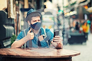 Tourist with face mask on video call from city center with friends