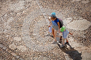 Tourist family walk on paved road in hot day, view from above