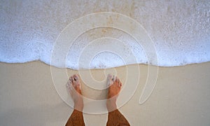 Tourist feet in tropical white sand beach