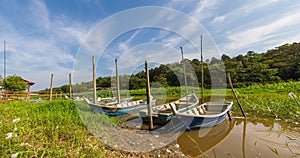 Tourist and fisher men boats on the bank. Veil clouds on the blue sky