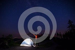 Tourist with flashlight near his camp tent at night