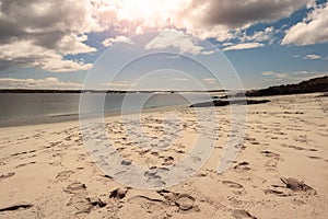 Tourist footprints on sand at Gurteen beach, county Galway, Ireland. Warm sunny day. Cloudy sky