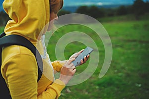 Tourist girl on background green grass using mobile smartphone closeup, women holding in female hands gadget technology, hiker