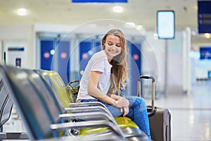 Tourist girl with backpack and carry on luggage in international airport, waiting for flight