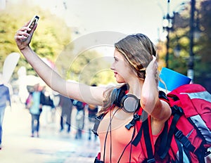 Tourist girl with backpack and headphones taking selfies on smartphone