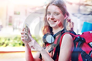 Tourist girl with backpack and headphones taking selfies on smartphone