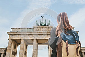 A tourist girl with a backpack looking at the Brandenburg Gate in Berlin photo