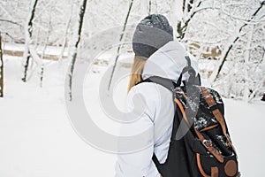 Tourist girl with backpack standing near at the entrance of a hotel, travel at New Year concept