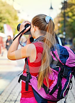 Tourist girl with backpack taking pictures on digital camera