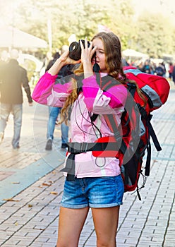 Tourist girl with backpack taking pictures on dslr camera