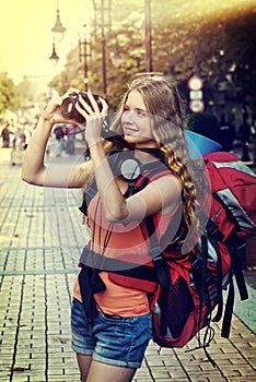 Tourist girl with backpack taking pictures on dslr camera