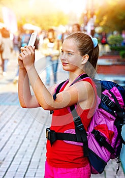 Tourist girl with backpack taking selfies on smartphone