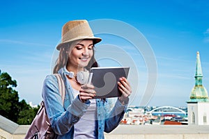 Tourist girl in denim shirt with tablet. Summer city.