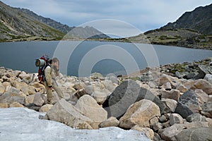 Tourist girl eating snow near a mountain lake