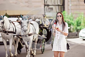 Tourist girl enjoying vacation in Vienna and looking at the beautiful horses in the carriage