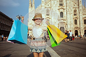 Tourist girl in front of Duomo showing colorful shopping bags