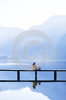 Tourist girl in a hat and with a backpack sitting on a wooden bridge