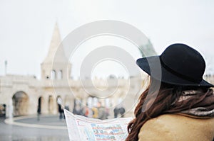 Tourist girl in hat looking on the map on Fisher Bastion in Budapest, Hungary