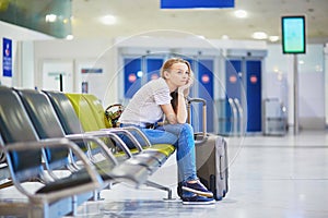 Tourist girl in international airport, waiting for her flight, looking upset