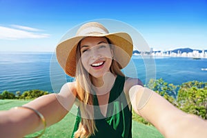 Tourist girl on Morro do Careca hill having fun takes self portrait on her summer vacation in Balneario Camboriu, Brazil
