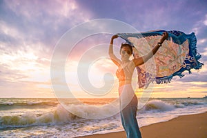 Tourist girl relaxing with blowing cloth in sunset on beach
