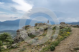 A tourist girl standing on a rock and admires the Demerdzhi mountain range on the Crimean peninsula