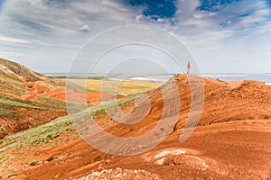 A tourist girl standing on the side of the Bolshoi Bogdo mountain on the background of the salty lake Baskunchak