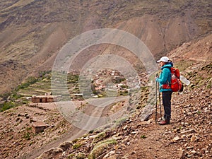 Tourist girl standing on the touristic path near Imlil over Tacheddirt village and looking into the valley
