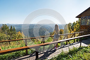 A tourist girl stands on the slope of mountain Church and looks down on the resort town of Belokurikha. Altai Krai, Russia. Young