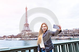 Tourist girl taking selfie in front of Eiffel Tower, Paris