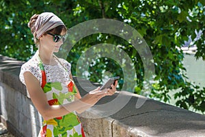 Tourist girl touching screen of tablet computer on green city alley