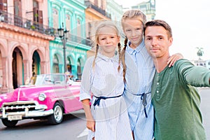 Family in popular area in Old Havana, Cuba. Portrait of two kids and young dad outdoors on a street of Havana