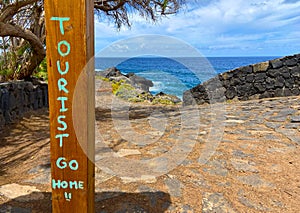 Tourist Go Home graffiti on ocean beach background.Stop mass tourism concept.Tourismophobia in Tenerife,Canary Islands,Spain.