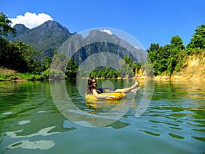 Tourist going down Nam Song River in a tube surrounded by karst