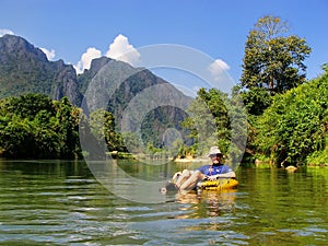 Tourist going down Nam Song River in a tube surrounded by karst